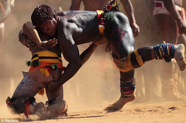 Gripping: Two tribe members, dressed in colourful robes, wrestle in the dust during the ritual