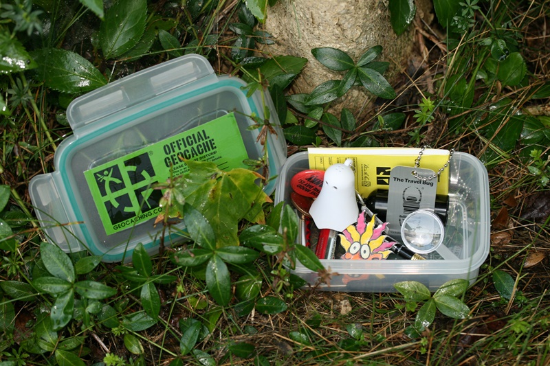 A sample small geocache, containing a pencil, a logbook for finders to sign, batteries and toys (which finders may take, leaving in exchange items they bring), and a travel bug, which may be tracked online as it moves from cache to cache across the country or around the world.